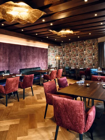 Modernes Restaurant mit Samtstühlen, Holztischen und farbenfroher Wanddekoration